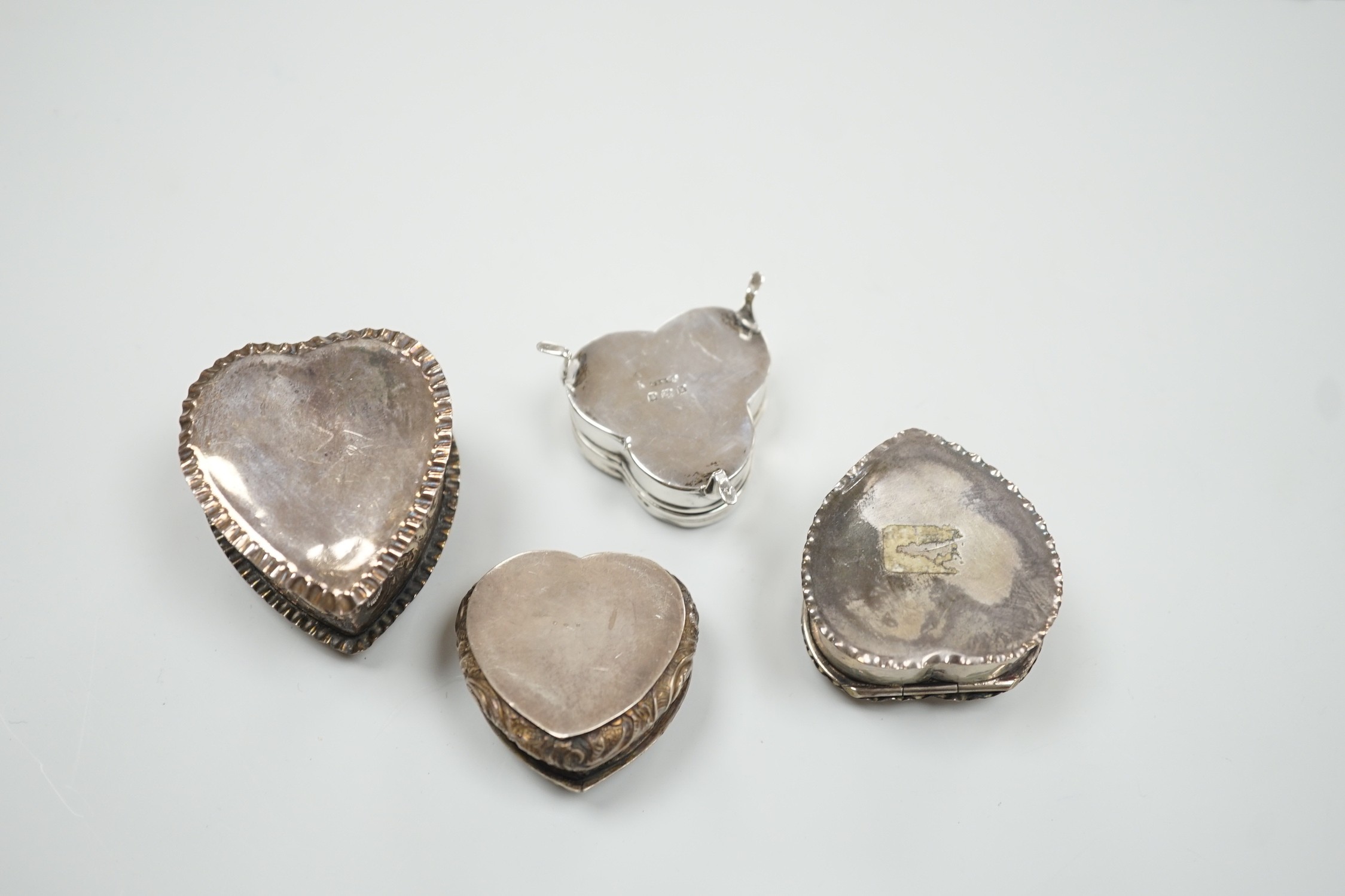 Three Victorian/Edwardian repousse silver heart shaped trinket boxes, largest 56mm and a similar mother of pearl inlaid 'pansy' trinket box, by Saunders & Shepherd, gross weight 1106 grams.